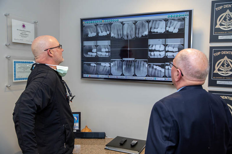 Charlotte dental arts dentist dr porter showing balding elderly white male patient digital x-rays of his dental implants