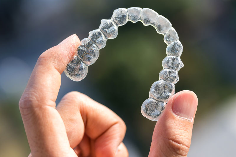 a dental patient holding an invisilign clear retainer.