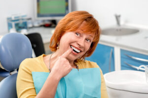 Smiling senior woman with new dental implants sitting in the dental office