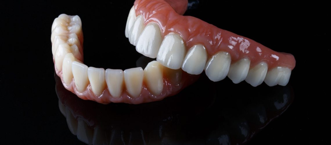 ceramic prosthesis with artificial gums, upper and lower jaw on black glass