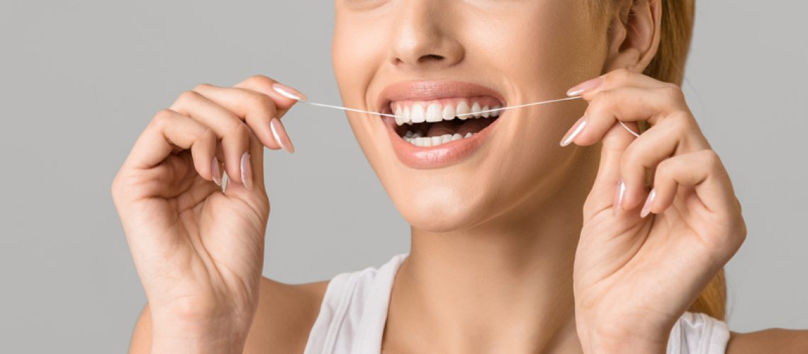 Close up photo of a woman flossing her teeth